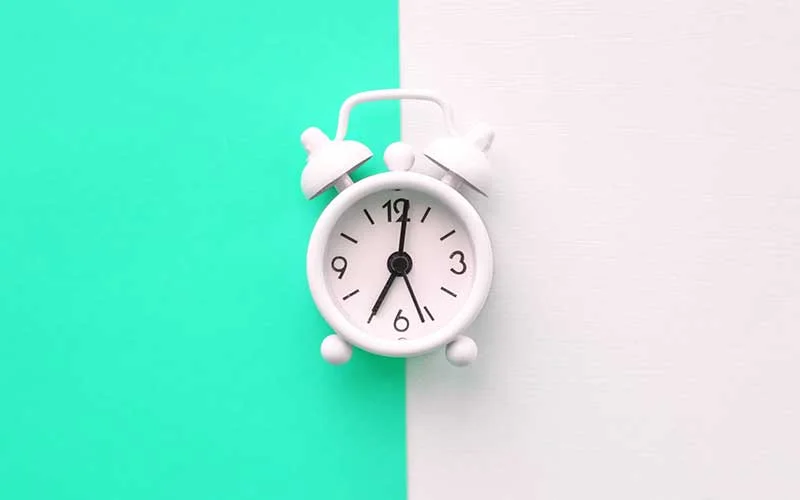 White alarm clock on green and blue background