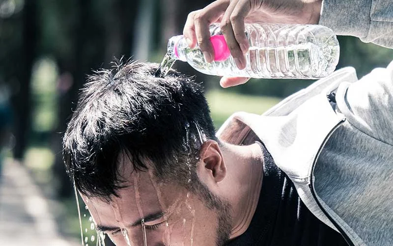 A man refreshes himself after exercising by pouring clean water on his body