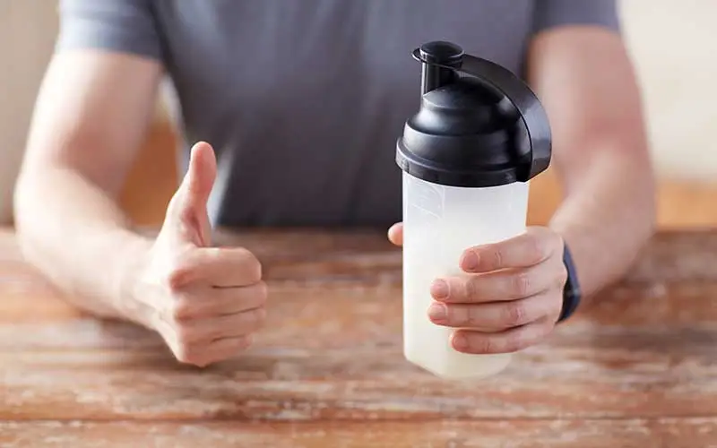 Man holding bottle of meal replacement shake and showing thumbs up