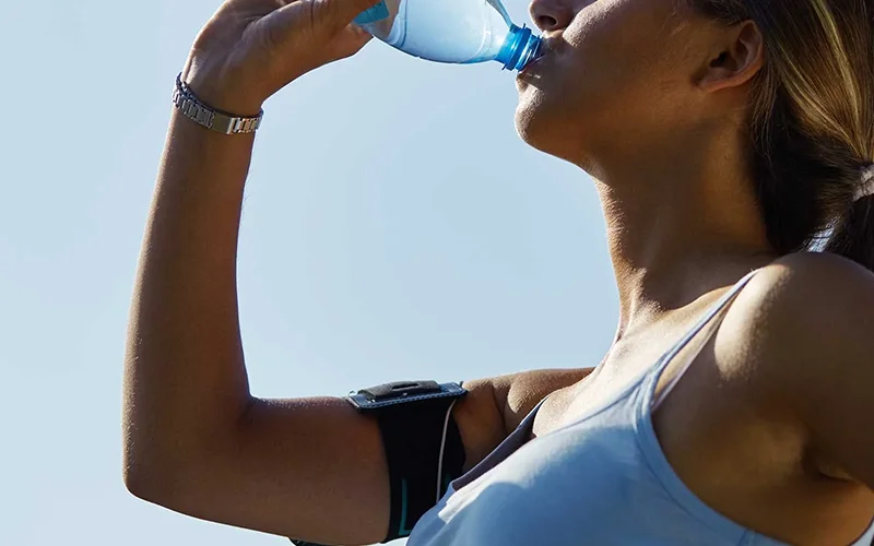 Beautiful young woman drinking water after workout