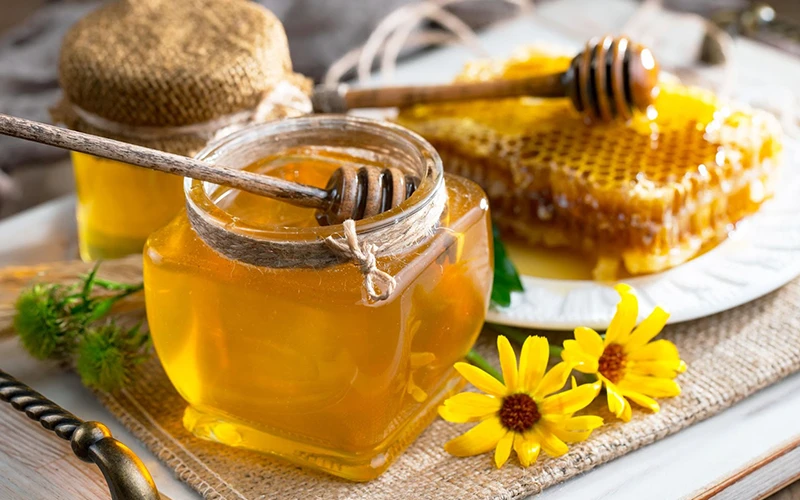 Fresh honey in a jar and honeycombs on a wooden background