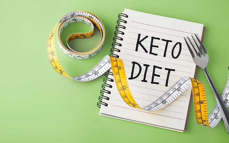 Keto diet concept on green background with measuring tape