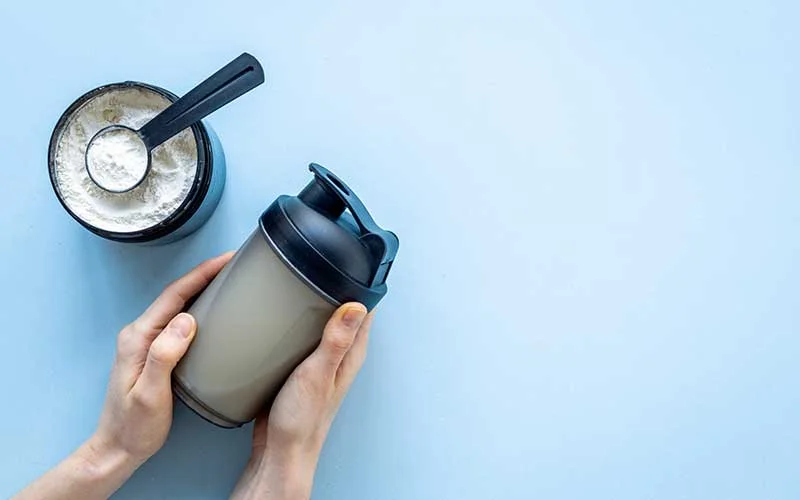 Sport shaker bottle in hands and keto shake in jar