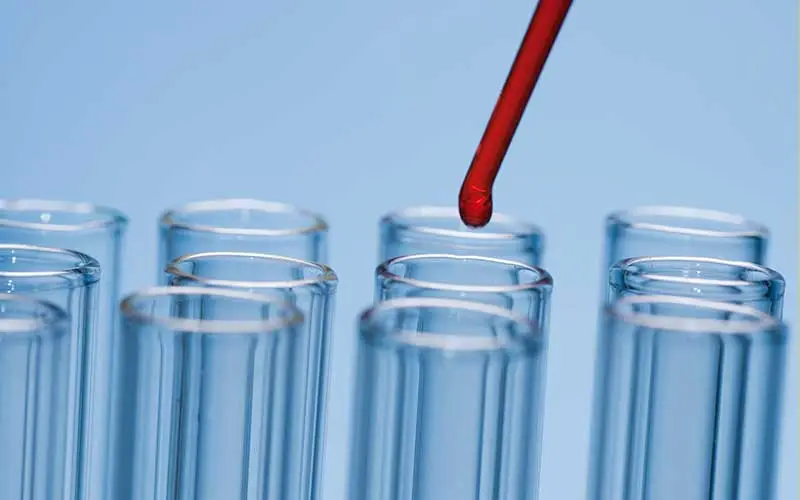 Laboratory test-tubes with red liquid on blue background.