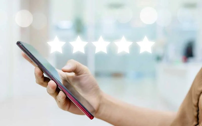 Woman use of smart phone with five star rating on bokeh background.