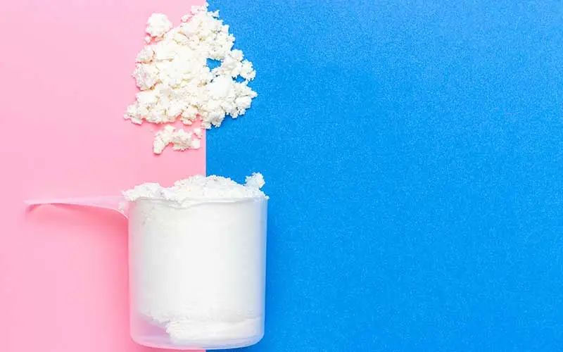 Meal replacement shake in a measuring scoop on a blue and pink background