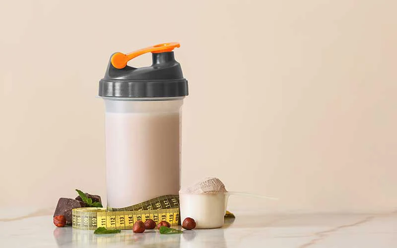 Bottle of meal replacement shake with measuring tape on light table