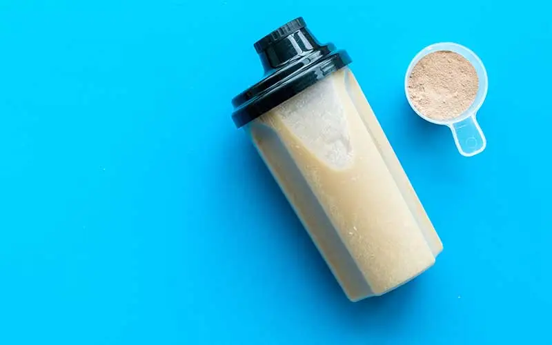 Meal replacement shake powder for cocktail and scoop on blue desk