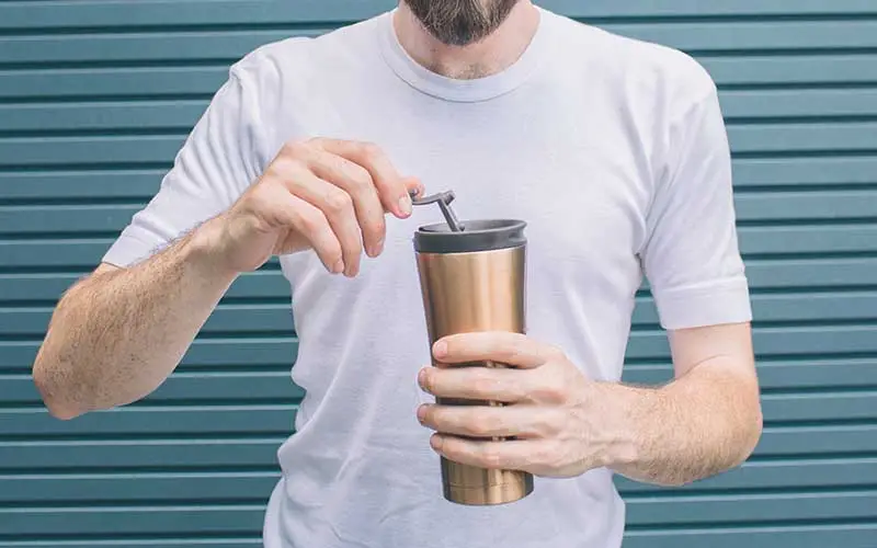 bearded man in white t-shirt is holding a shaker