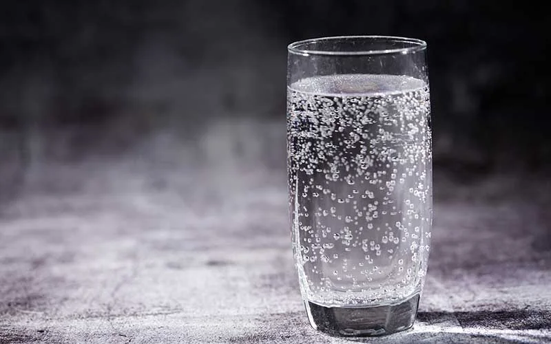 Glass of carbonated drink on the gray background