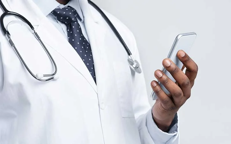 A doctor with a stethoscope and smartphone in his hand