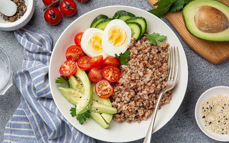 healthy vegan lunch bowl with avocado, egg, cucumber, tomato and buckwheat