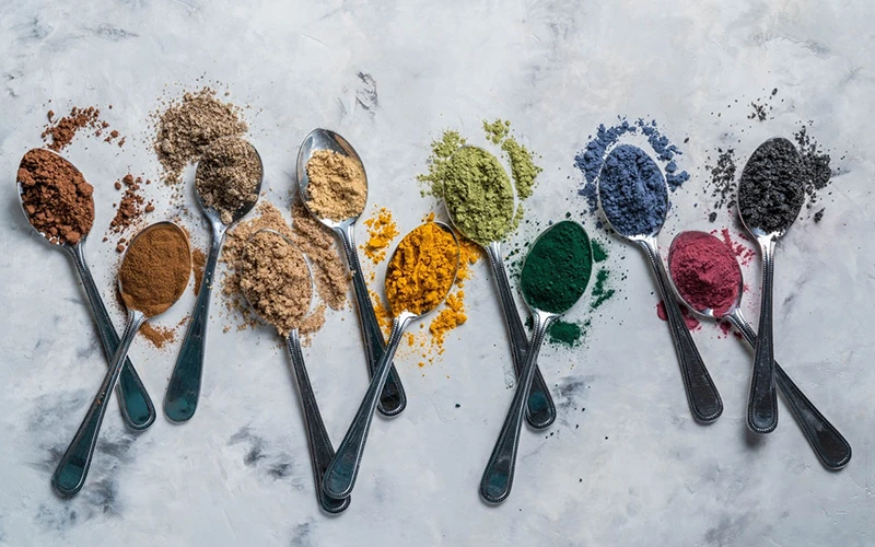 Superfood powders in spoons on marble background