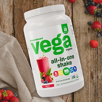 Vega One All-in-One Shake and berries on wooden background