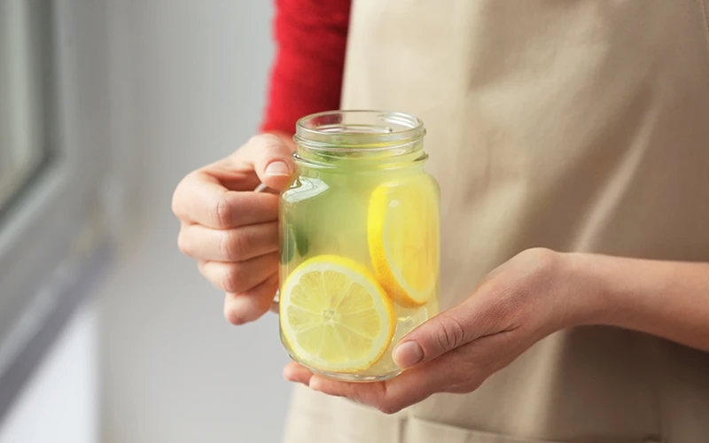 Woman holding glass jar with lemonade closeup